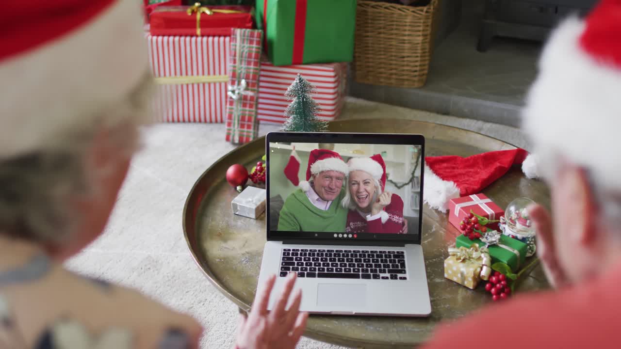 pareja caucásica de alto nivel con sombreros de santa usando una computadora portátil para una videollamada de navidad con pareja en la pantalla