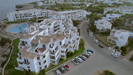 a rotating aerial view captures a complex of tourist accommodation buildings situated along the coastline of mallorca, spain, embodying the concepts of tourism and vacation