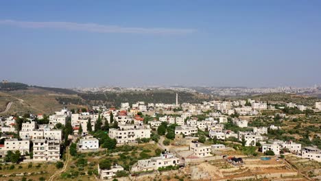 aerial view of a village nestled in hills with a distant city skyline