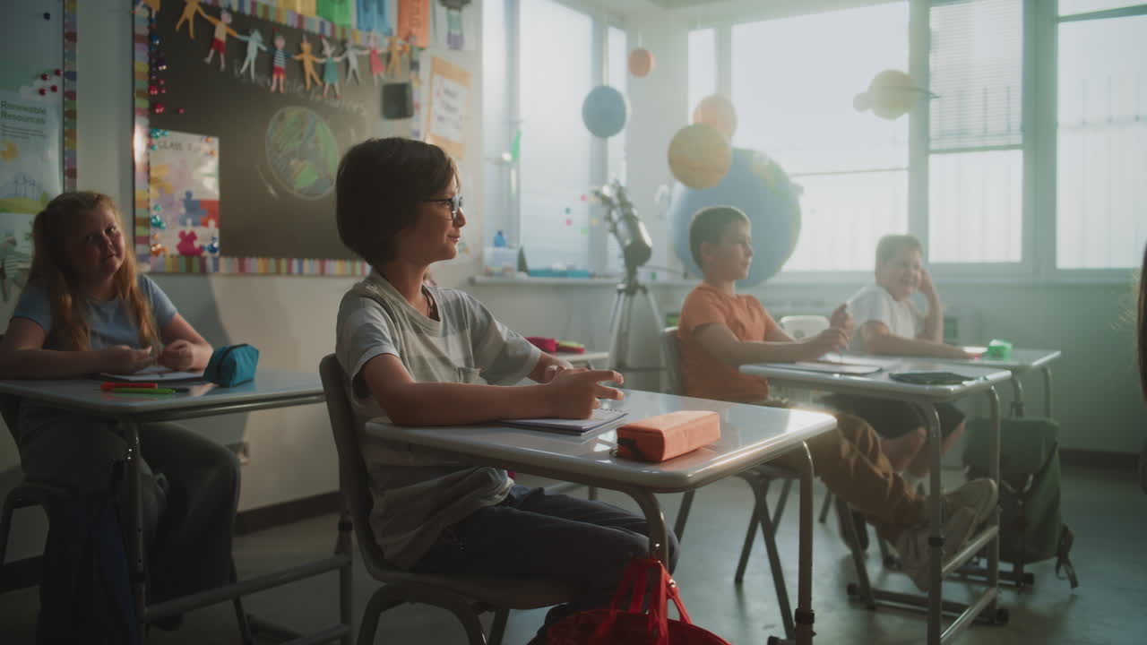 Elementary School Students Sitting at the Desks Writing School Test or Lecture in Notebooks