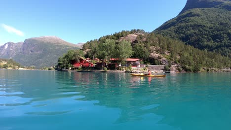 Female-brunette-paddling-through-turquoise-glacial-lake-in-outstanding-beautiful-Norway-landscape-during-summer-vacation---Loen-Norway-handheld