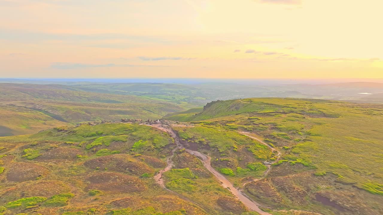 Aerial landscape over B-29 crash site in High Peak, England, sunset glow on green rolling moorland hills.