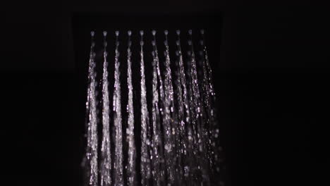 el agua fluye de una boquilla cuadrada negra en la ducha.