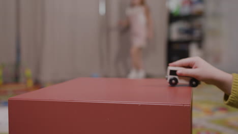 Close-Up-View-Of-Hands-Of-Two-Children-Playing-With-A-Wooden-Car-In-Classroom-In-A-Montessori-School