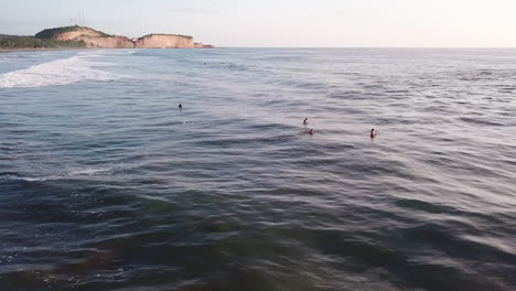 drone volando sobre los surfistas surfeando en la playa de olon en ecuador