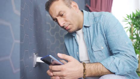 un primer plano de un hombre enchufando un enchufe eléctrico en un enchufe de pared.