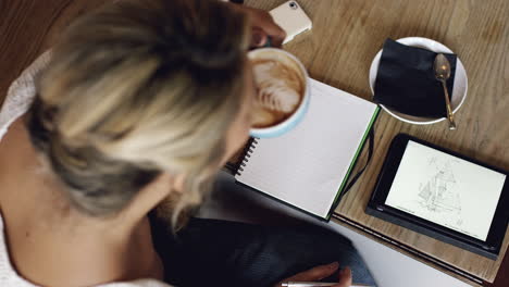 Architect-woman-working-in-cafe-drinking-coffee-high-angle