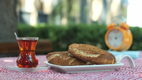 turkish simit served with turkish tea. and an orange clock.