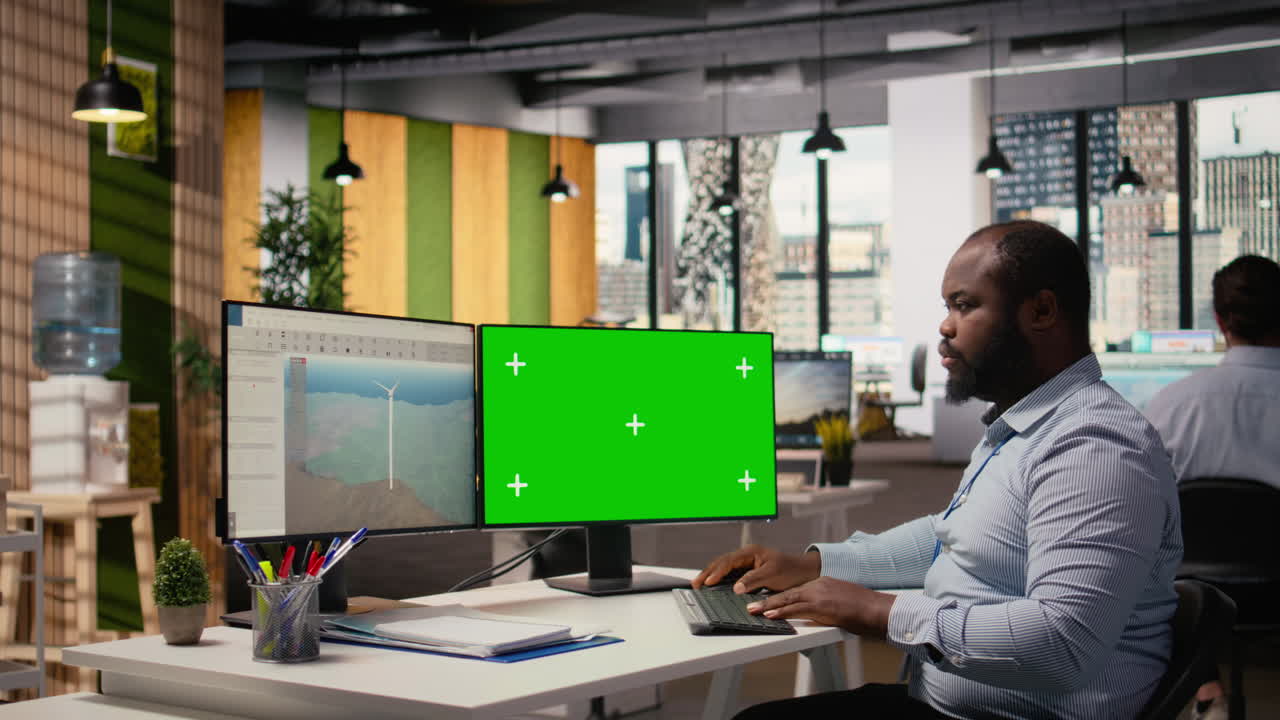 Forsker arbejder på futuristisk vindmølle på pc med grøn skærm.