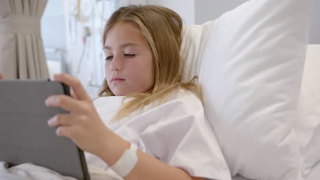 caucasian girl patient sitting up in hospital bed using tablet, slow motion