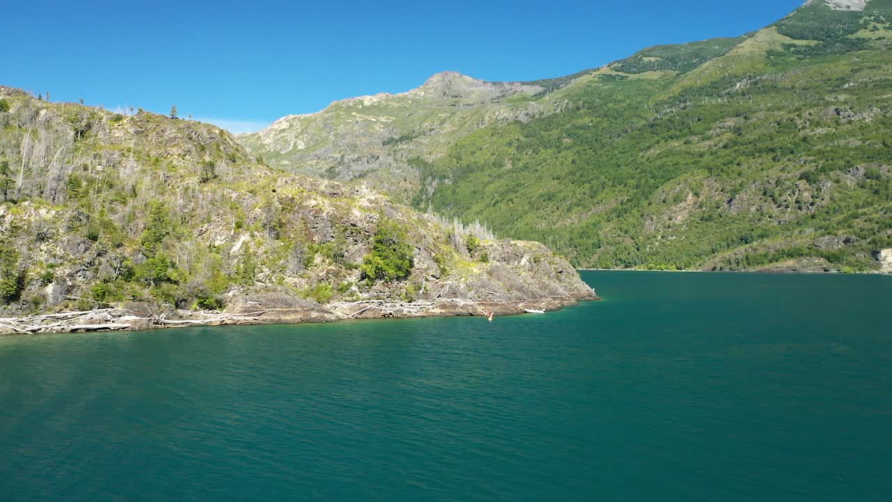 푸엘로 호수의 바위 해안 근처에서 카약을 타는 사람의 공중 돌리, 배경의 산, 아르헨티나 파타고니아이