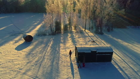 Wooden-shelter-in-winter-landscape-with-people-walking-on-snow