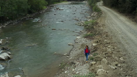 turista caminando río rocoso vista de avión no tripulado en un día nublado y frío divirtiéndose montañas