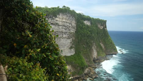 wide shot of a cliff with waves breaking below in uluwatu, bali