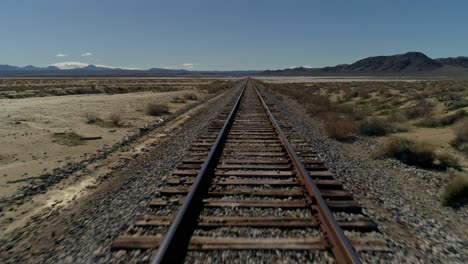 fast, overhead, pull back aerial view of straight railroad tracks in the desert