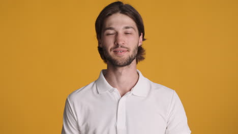 caucasian man waving at camera on yellow background.