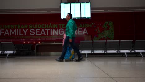 Man-walking-with-luggage-in-front-of-information-board-at-Dublin-airport