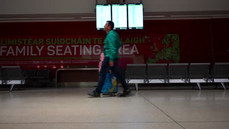 hombre caminando con equipaje frente al tablero de información en el aeropuerto de dublín