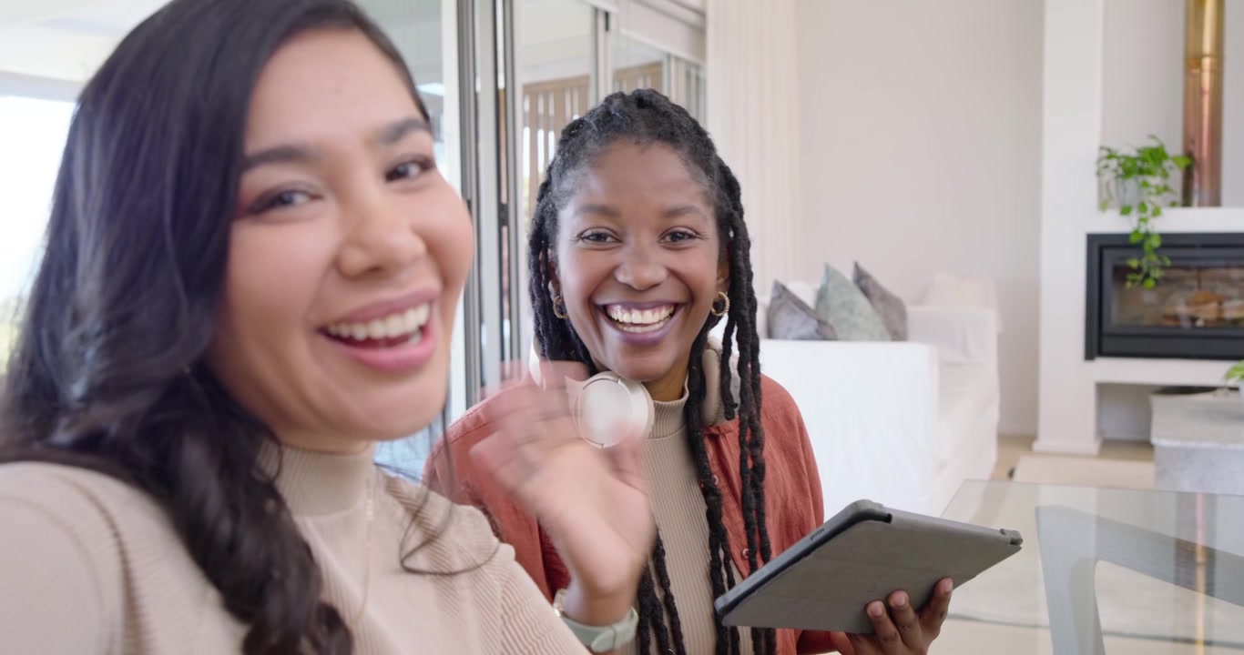 Donne di diverse etnie che premono "registra" sul telefono per un vlog a casa, parlando alla telecamera, sorridendo e toccando un tablet