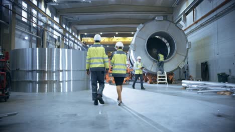dos ingenieros de la industria pesada caminan a través de la fábrica de fabricación de tubos. instalación para la construcción de productos de transporte de oleoductos, gasoductos y combustibles.