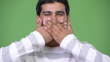 young handsome persian man covering mouth as three wise monkeys concept