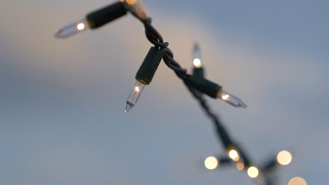 close up of christmas lights strung outside in the summer during dusk