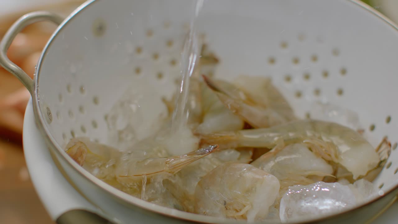 Rinsing Raw Shrimp in a Strainer Bowl Under Running Water