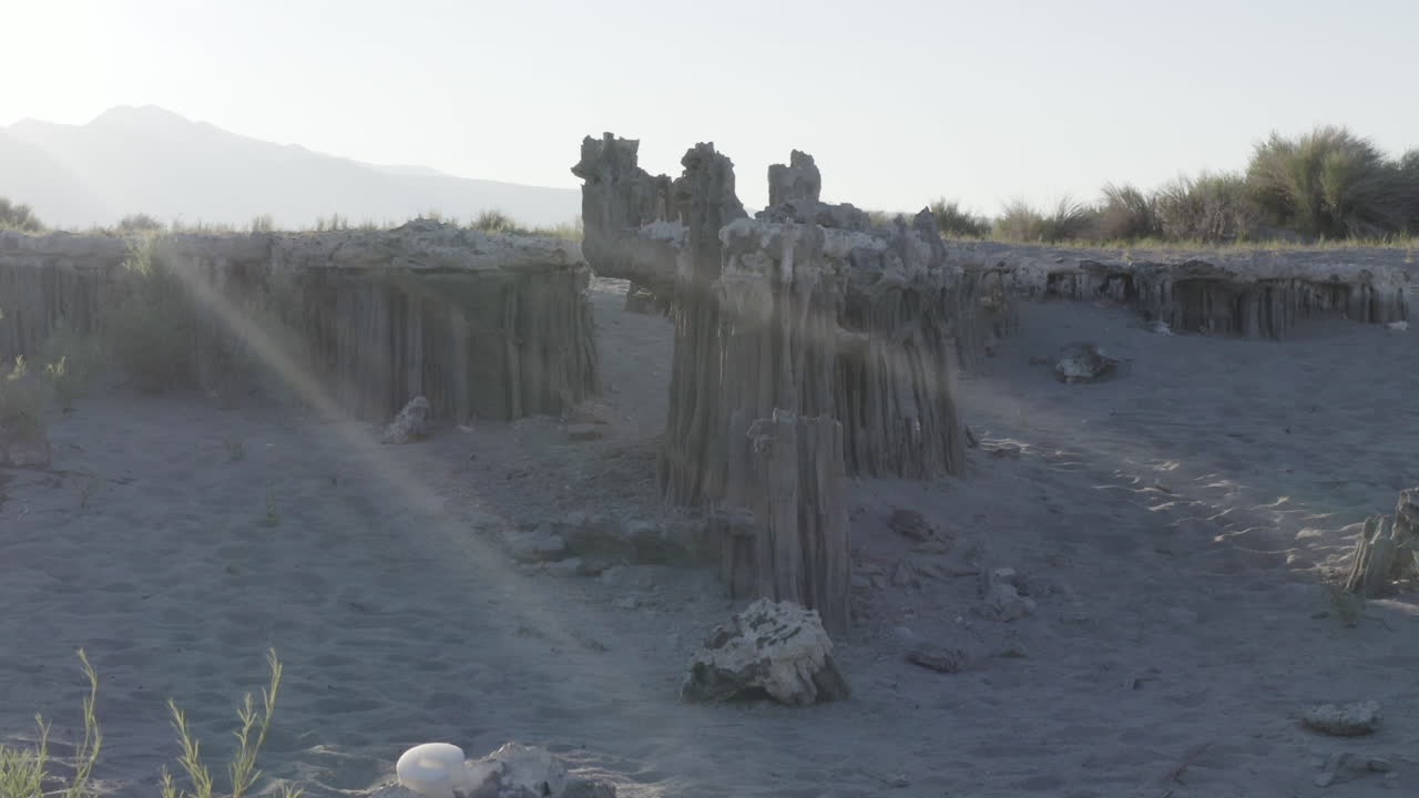 모노 호수 (mono lake) 의 토프 기둥의 공중 풍경, 밝고 은 하늘 아래의 조용한 물과 먼 산에 대한 독특한 모양과 질감을 강조합니다.