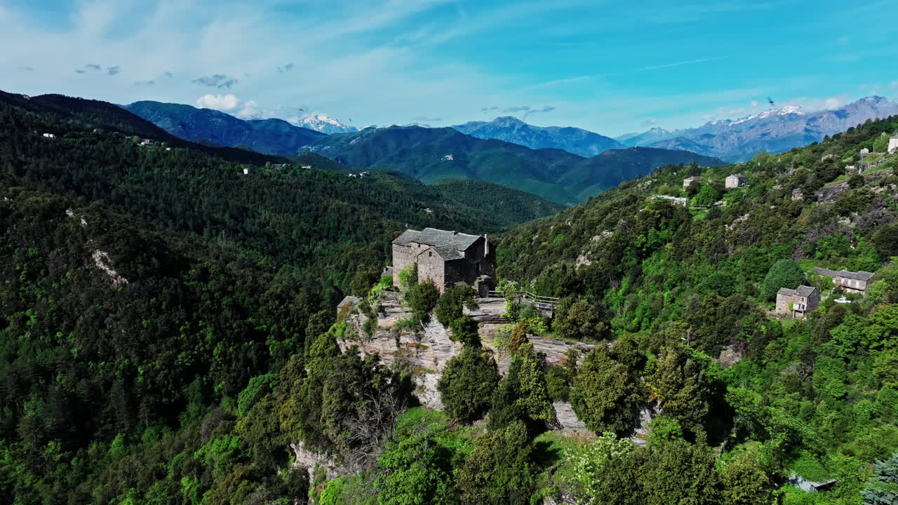 Aerial drone shot over the green lush landscape of inland Corsica, France. High view of the landscape and the mountains in the distance. Summer holidays destination for hikers and mountain lovers