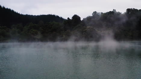 slow aerial over vapor rising from steamy geothermal lake in new zealand, north island