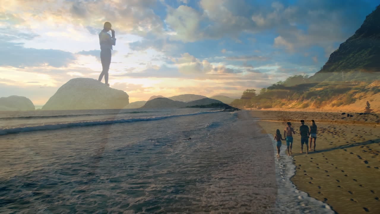 Standing on rock, person overlooking family walking on beach at sunset animation