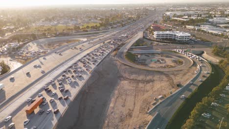 Lapso-De-Tiempo-Aéreo-De-La-Ajetreada-Autopista-405-Durante-La-Hora-Punta-Con-Tráfico-Intermitente-Y-Camiones-Que-Entran-Y-Salen-De-Las-Rampas-En-Medio-Del-Bullicioso-Paisaje-Urbano