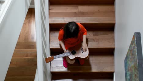 Girl-holding-guitar-while-sitting-on-staircase-4k