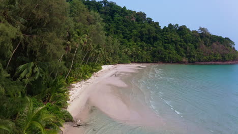 person standing on white sand koh kood beach in tropical ocean lagoon