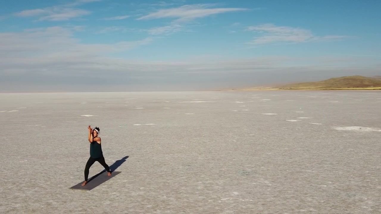 Bella ragazza bruna che pratica Yoga in un paesaggio selvaggio. Flusso Vinyasa con asana del Guerriero I e Guerriero Umile. Buone vibrazioni ed energia - Lago Tuz, Salar in Turchia.