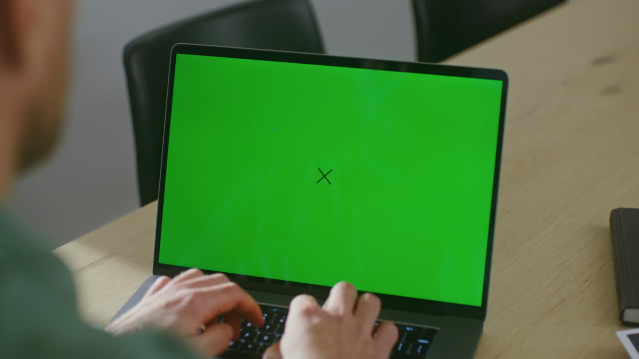 un joven está escribiendo en una computadora portátil con una pantalla verde, tecla de croma, espacio de copia