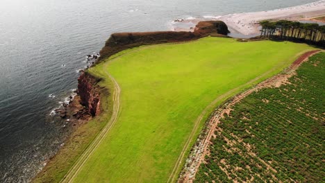 aerial over open green landscape with budleigh salterton beach in background