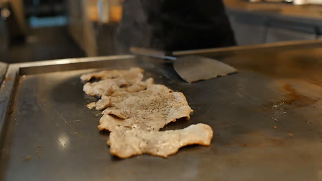 close-up of a skilled chef preparing teppanyaki japanese cuisine on a hot iron griddle in front of guests, grilling fresh ingredients with flair. perfect for japanese food culture and live cooking