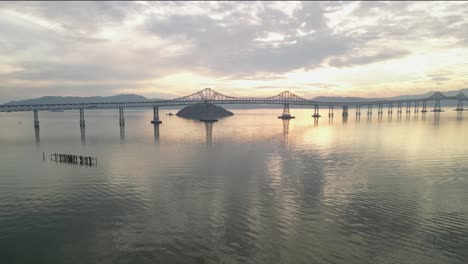 high angle aerial overview of yellow sunset light glistening on calm waters of richmond bridge from point molate beach richmond california usa