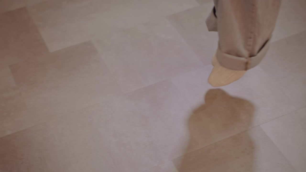 Primer plano de pies con calcetines practicando en estudio, estudiante de música ensaya pasos inspirados en el claqué bajo la guía paciente de un entrenador, vaqueros holgados rozando el suelo de madera, luz suave, repetición concentrada, entrenamiento de ritmo.