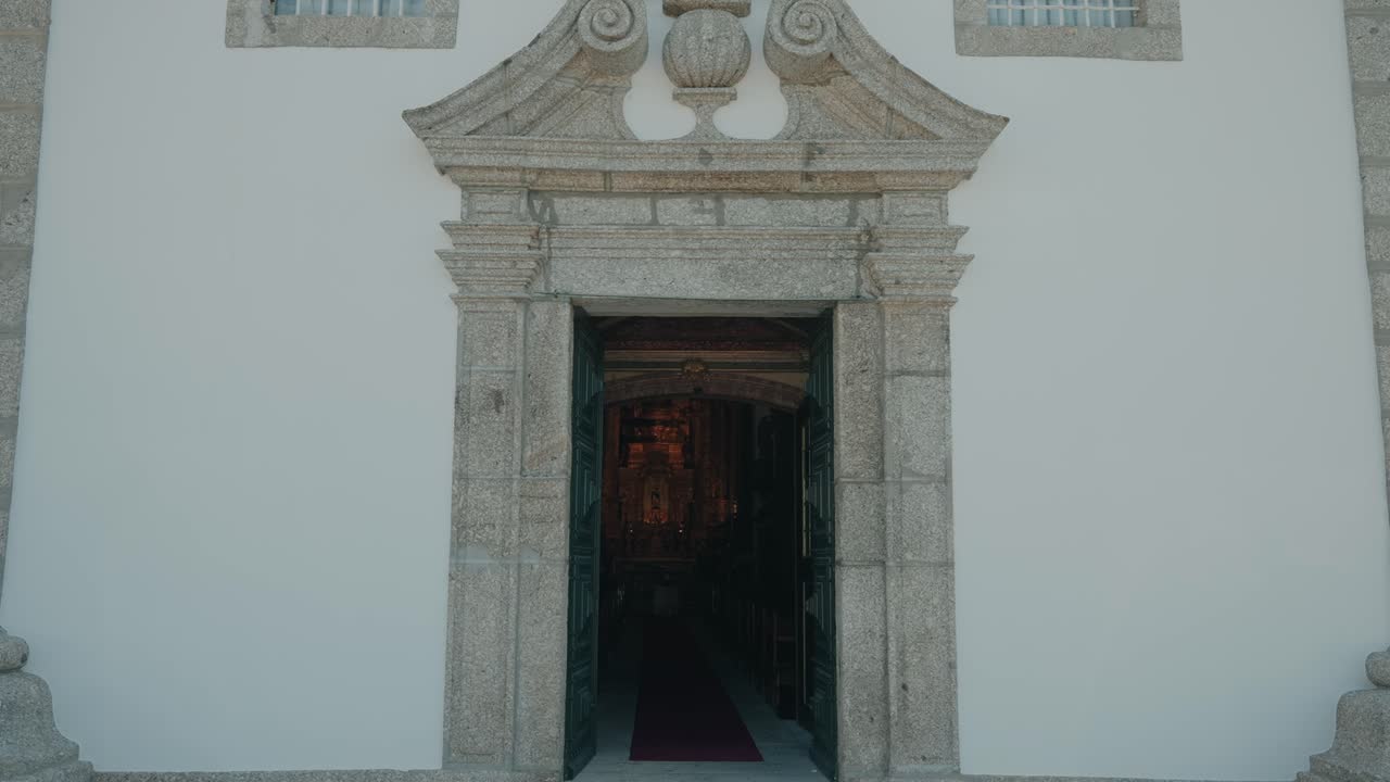 Vista frontal de la entrada de una iglesia con las puertas abiertas y la nave interior
