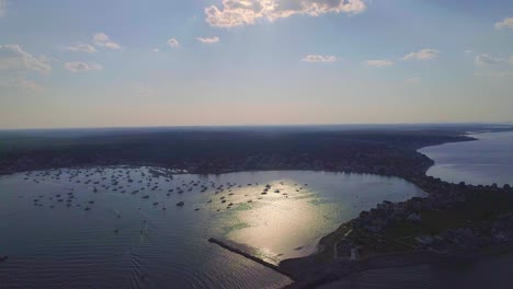 Massachusetts-harbor-with-boats-and-sailboats,-sunny,-far-away--Drone-video