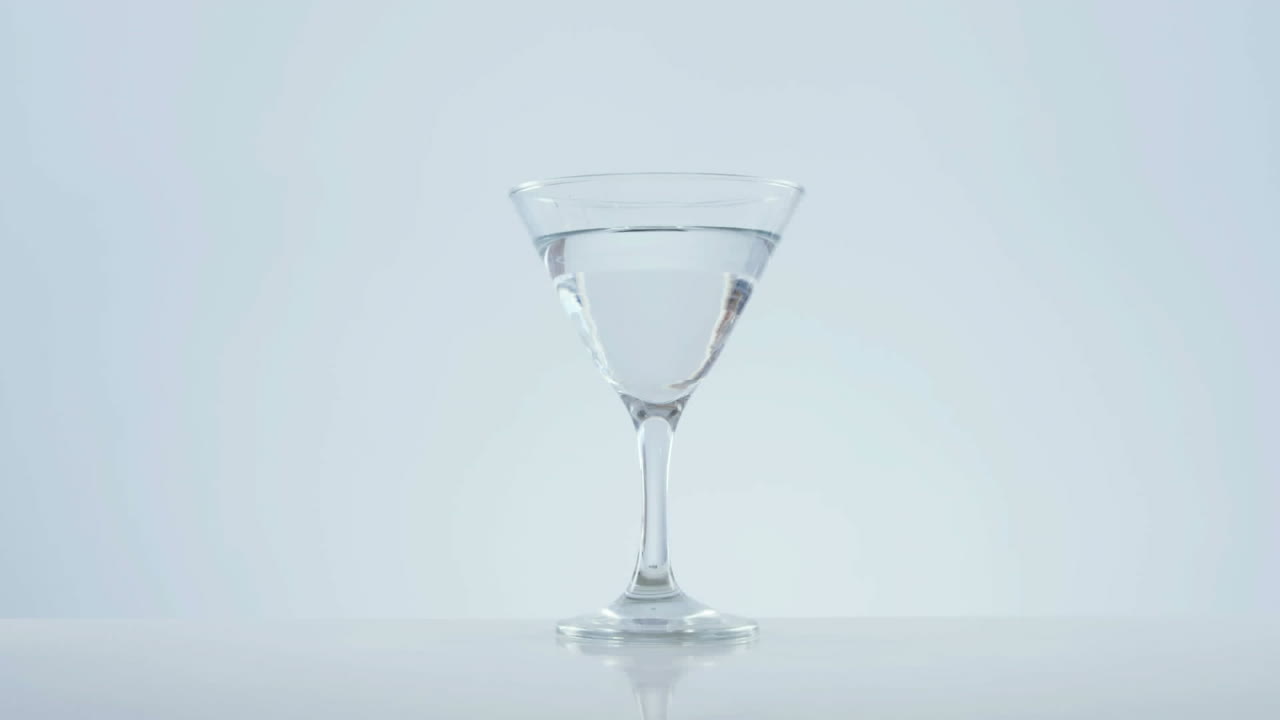 Animazione di puntini rossi che si muovono su un bicchiere da cocktail con olive su sfondo bianco.
