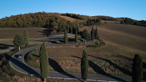 suv conduce a lo largo de la carretera sinuosa que pasa a través del paisaje toscano, dolly aéreo