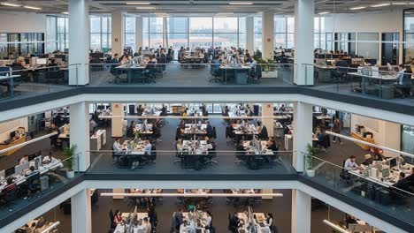 a modern office space showcasing multiple floors of workstations, employees collaborating, and a bright, open environment enabling productivity and innovation