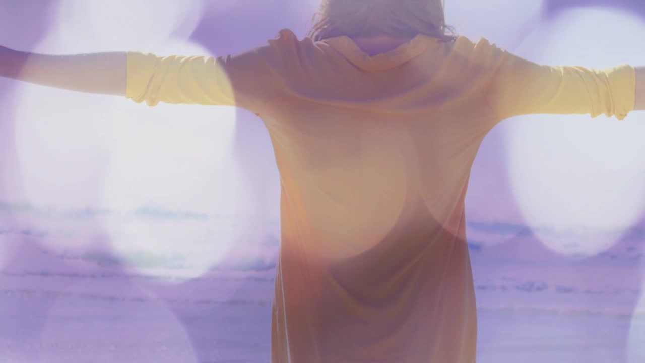 Woman barefoot pushing from board toward sea, yellow shorts balancing amid purple bokeh travel