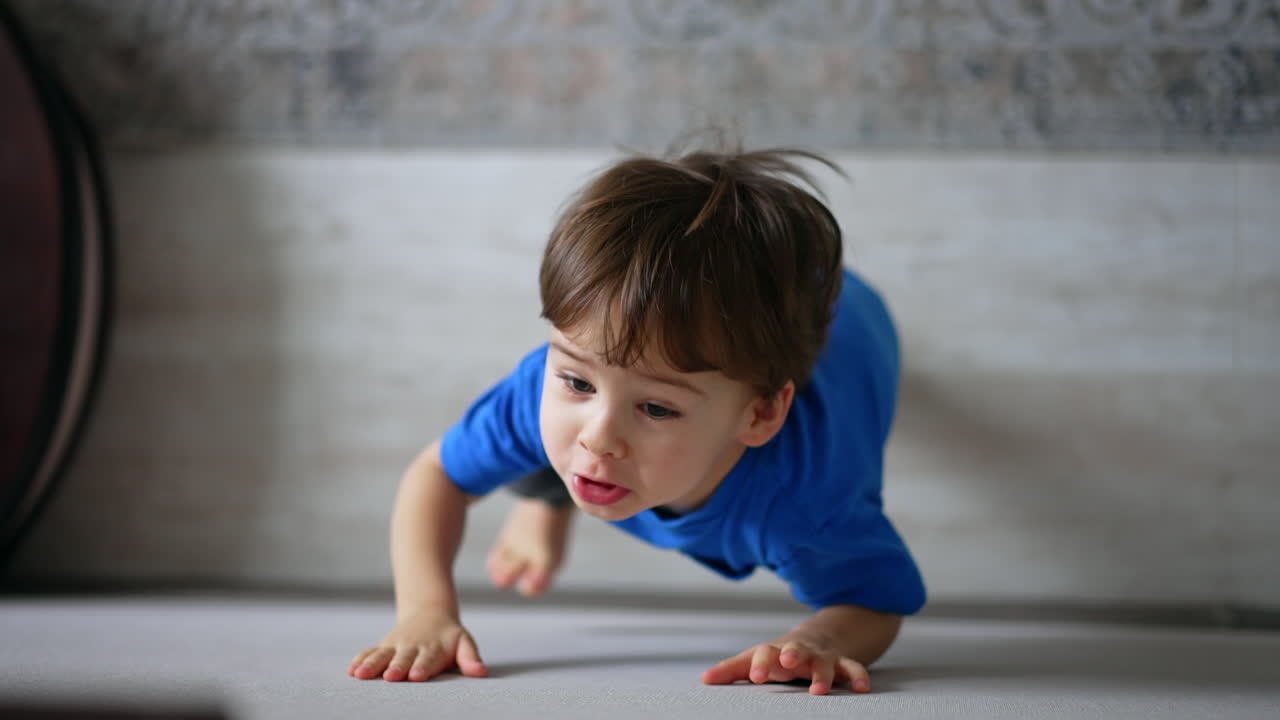 Adorable Caucasian toddler standing at the wall looking up. Top view of a kid at home.