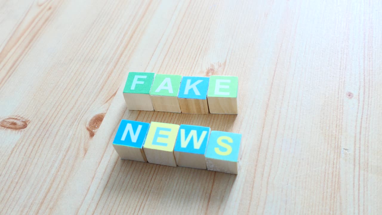mano trayendo noticias falsas escritas en cubos de madera