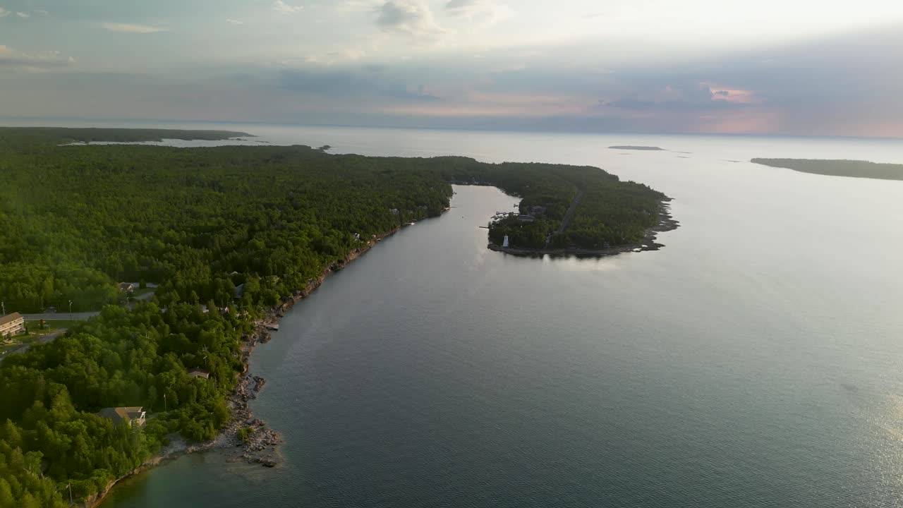 Aerial View of a Lush Green Peninsula and Calm Waters with a Lighthouse