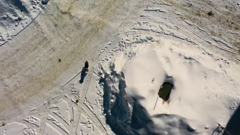 perro ladrando a drone en las casas del vecindario de invierno cubiertas de nieve mientras camina por las carreteras y caminos sinuosos en la ciudad de montaña, vista aérea de arriba hacia abajo del drone